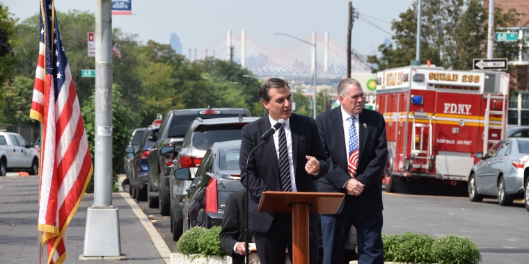 Senator Gianaris, standing next to an American flag and a fire truck delivers remarks at a September 11 Memorial ceremony in Maspeth