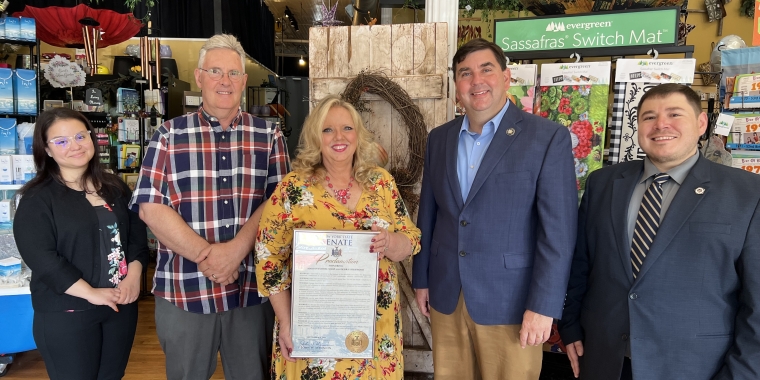 Senator Mannion with Maida's Floral Shop owner Debra Sherwood and others giving a framed proclamation.
