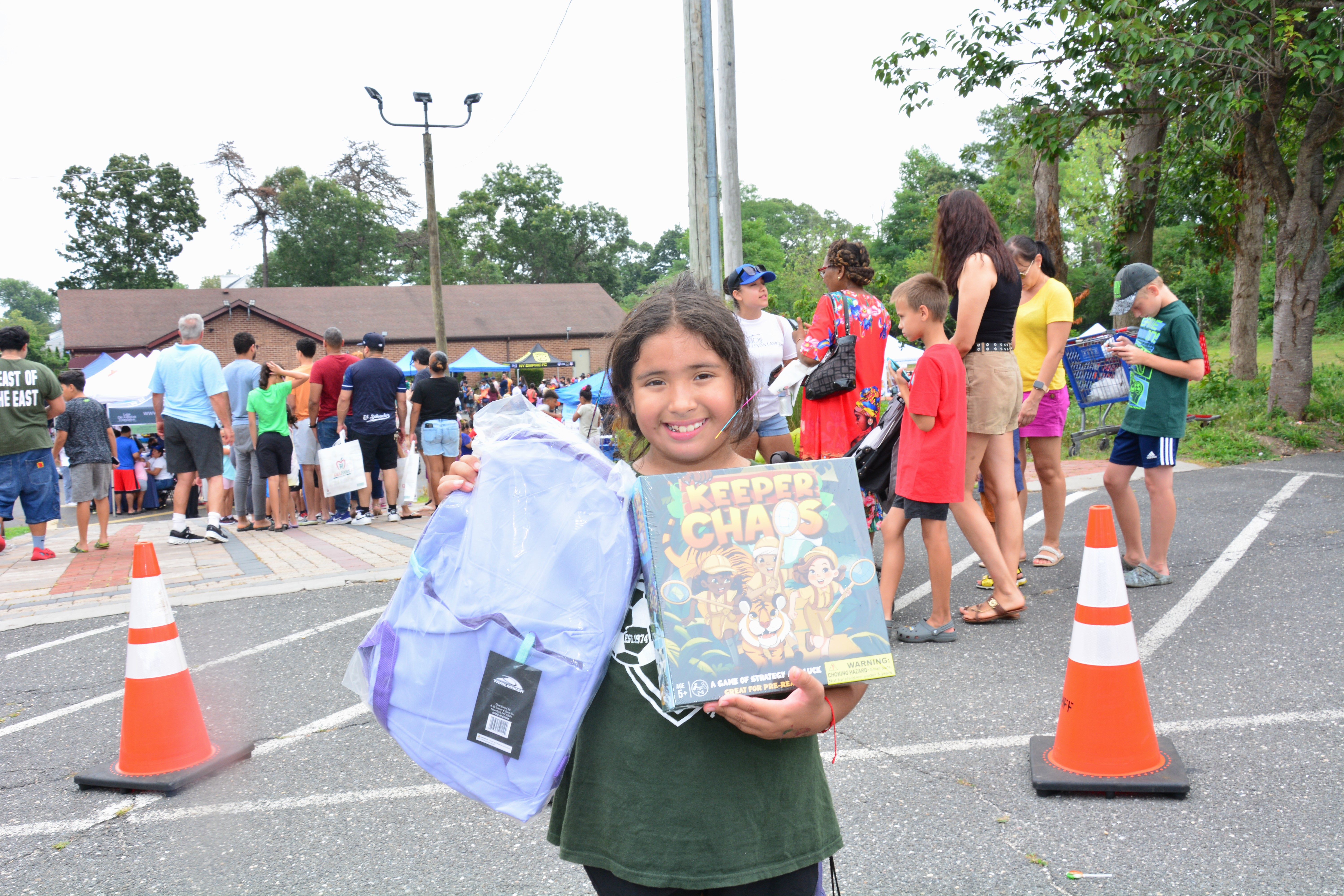Photo of student holding a backpack and a book given out at the Brentwood backpack and school supply event on Saturday, Aug. 16, 2025.