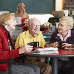 A group of older adults chatting at a cafe