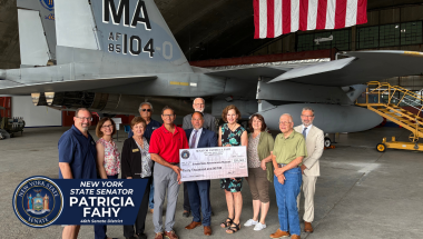 Senator Fahy and ESAM representatives in front of a F-15C fighter jet with large check