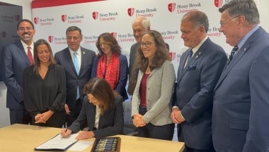 Photo Image of Gov. Kathy Hochul signing a bill sponsored by Sen. Martinez that allows Stony Brook University to develop more on-campus housing.  The governor is surrounded by officials including Sen. Martinez during the signing.