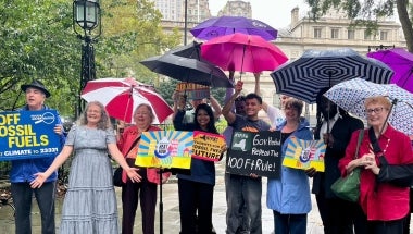 Advocates stand under umbrellas at a press conference