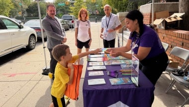Senator Addabbo and QPL President and CEO Dennis Walcott join QPL staffers as they give away free books and other goodies.
