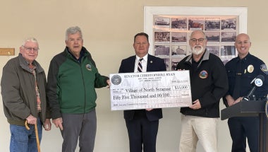 Group of people standing together with a check presentation for $55,000 to the Village of North Syracuse Police Department