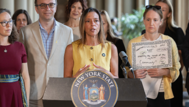 New York State Senator Monica R. Martinez speaks from a podium during a May 20, 2026, press conference with lawmakers and advocates calling for updated health curriculum covering common menstrual disorders.