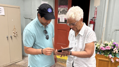 Tyler Singh, the Vice President of DMS International, helps a senior with her tablet at the Ozone Park Older Adult Center.