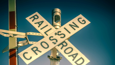 Photo Image of a railroad crossing sign with gate arm raised.