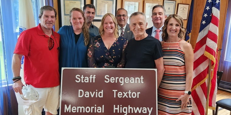 Photo of family & guests with 'Staff Sergeant David Textor Memorial Highway'