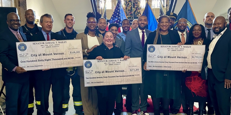 Group of people holding three checks.