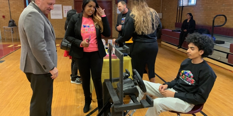 Senator Addabbo is joined by Keren Espinoza, owner of  Flavors Driving School, as her son Bryan Espinoza demonstrates their distracted driving crash test simulator.