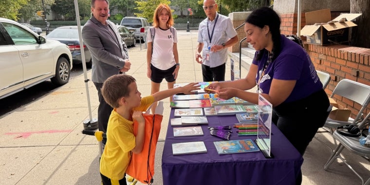 Senator Addabbo and QPL President and CEO Dennis Walcott join QPL staffers as they give away free books and other goodies.