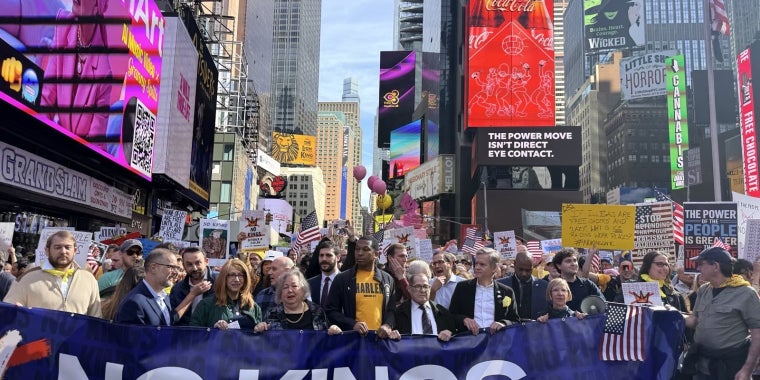Protestors stand in Times Square behind a banner that read "No Kings"