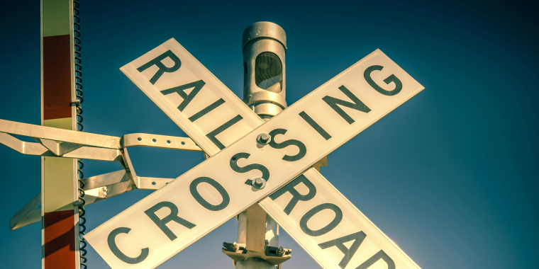 Photo Image of a railroad crossing sign with gate arm raised.