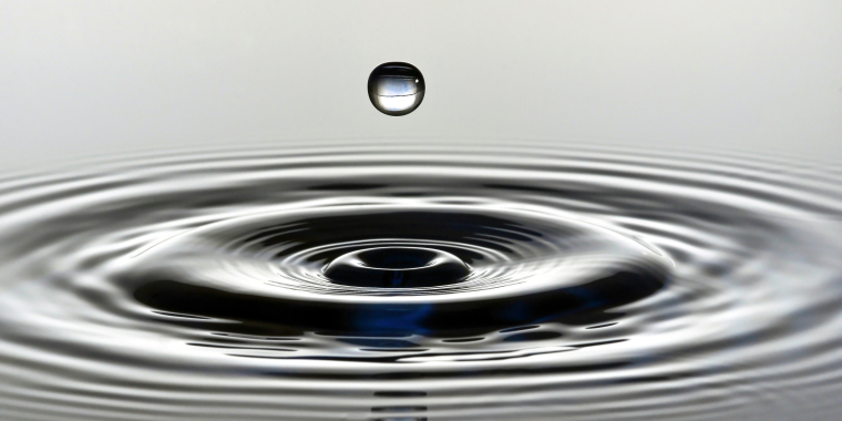 Photo image of a water drop and water ripples.