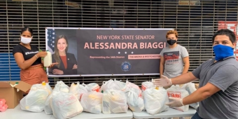 Team Biaggi stands in front of supplies and a banner of the Senator