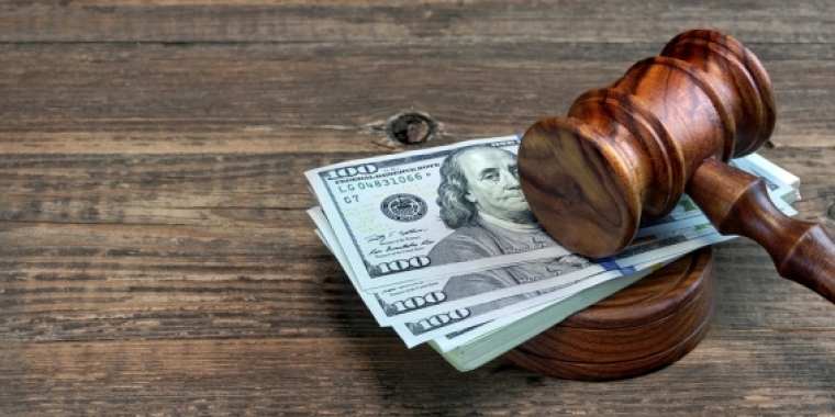 A gavel on a pile of one-hundred dollar bills.