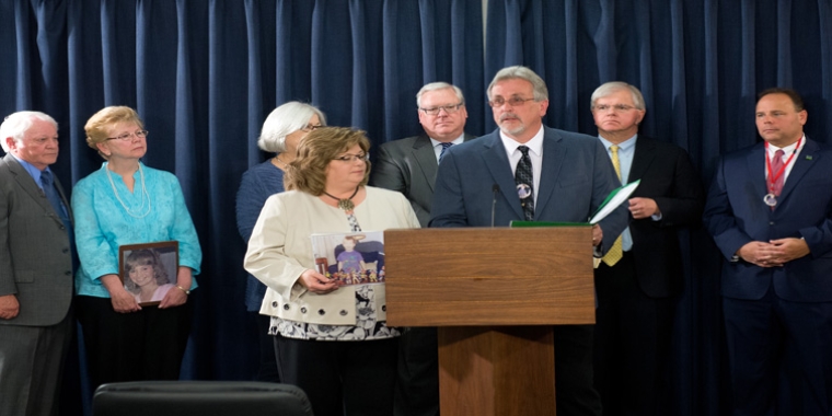 Dale and Dori Robie (holding a photo of their son Derrick) address today's news conference in Albany.