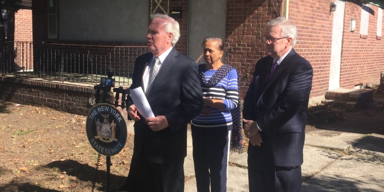 Senator Avella stands at site of abandoned house. Prior to today, derelict cars filled this driveway.