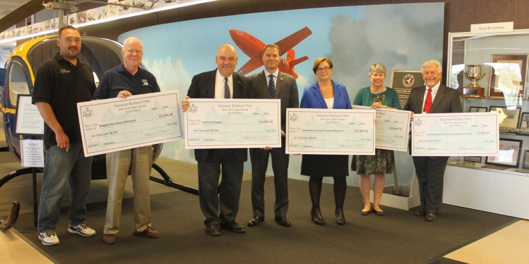 Pictured at the Niagara Aerospace Museum from left to right: Niagara Aerospace Museum Manager Jason Parfinski; Niagara Aerospace Museum Librarian Ray Meissner; Old Fort Niagara Executive Dir. Bob Emerson; Senator Rob Ortt; Herschell Carrousel Factory Museum Board President Reanna Darone; Niagara County Historical Society Executive Dir. Melissa Dunlap; and Historical Society of North German Settlements in WNY John Schultz.