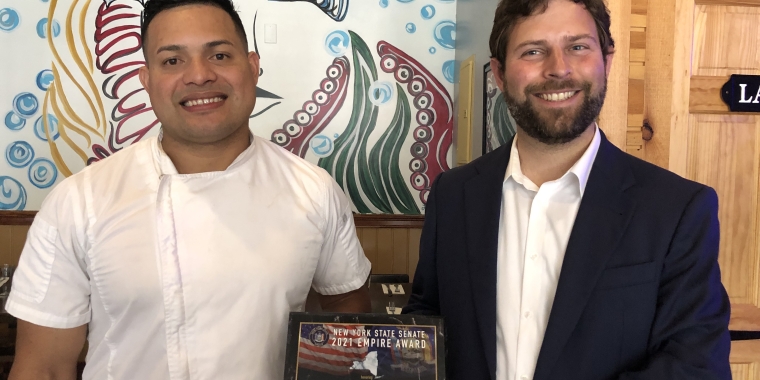 Senator Elijah Reichlin-Melnick presents a New York State Senate Empire Award to Elmer Oliveros, owner of Brothers Fish and Chips.