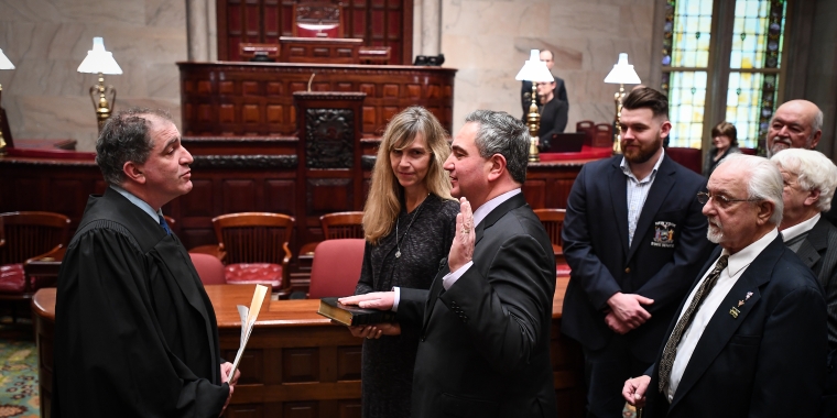 The Hon. David A. Weinstein administers the oath of office to Senator George Borrello. Senator Borrello’s wife, Kelly, holds the Bible as his family members look on.
