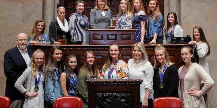 Senator Pam Helming stands with members of the Canandaigua Academy Braves cheerleading team that won the 2018 New York State D1 Small School Cheerleading Championship, Head Coach Laura Burgess, and Canandaigua City School District Athletic Director Jim Simmons during a ceremony in the New York State Senate chamber on Monday, April 16.