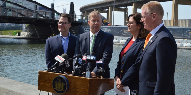 L-R: Explore & More Children's Museum CEO Douglas Love, Senator Chris Jacobs, Buffalo Heritage Carousel President Laurie Hauer-LaDuca and Buffalo & Erie County Naval & Military Park Executive Director Capt. Brian Roche announcing $1.5 million in state funding for the three major attractions. Directly behind is the construction site for the new Canalside location of Explore & More.