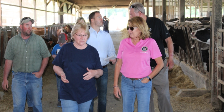 Senator Pam Helming chats with Peg Hilton during a tour of Hilton Farms, a family-owned dairy and crop farm in Hopewell, during a tour of the operation. In back, Senator Rob Ortt talks with New York State Farm Bureau Region 4 Senior Field Advisor Mark James.