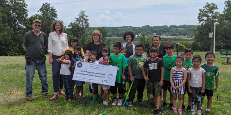 (Left to right) Farmer and WAMC Board Member, Chris Pawelski, Senator Jen Metzger, WAMC Executive Director, Katherine Brieger, and summer camp volunteers stand with a group of campers ages 6-8.