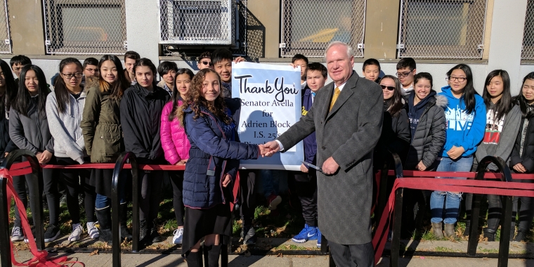 Senator Avella stands with Brianna Maher and classmates to celebrate the ribbon cutting of a new bike rack.
