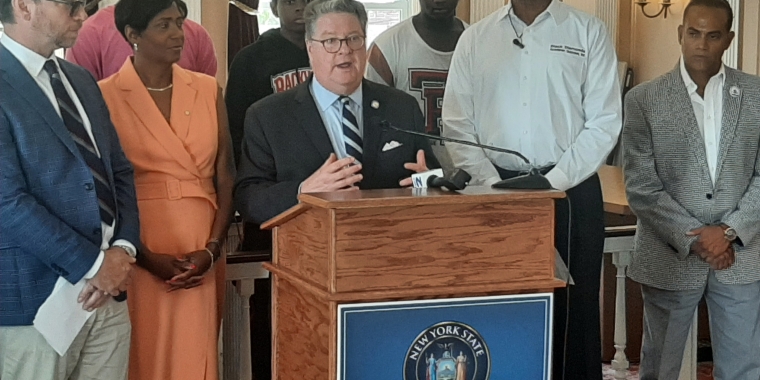 Sen. Harckham at the podium with (l-r) Peekskill City Manager Matthew Alexander, Mayor Vivian McKenzie, Black Diamonds Academic Success, Inc. Founder and CEO Martin McDonald and Peekskill Schools Superintendent Dr. David Mauricio. In second row: Black Diamonds members Malik Culberson, Nathaniel Martinez and Zamir Travis