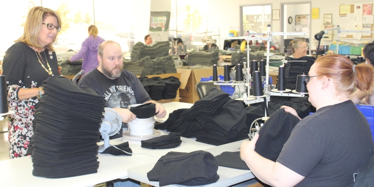 Senator Pam Helming talks with James Rice, left, and Sarah Farrow at Arc of Seneca Cayuga’s Finger Lakes Textiles business operation in Waterloo as they work on making wool hats for the U.S. Army on Monday, Oct. 23. As well as working at Finger Lakes Textiles, Mr. Rice is President of the Arc of Seneca Cayuga’s Self Advocates group.