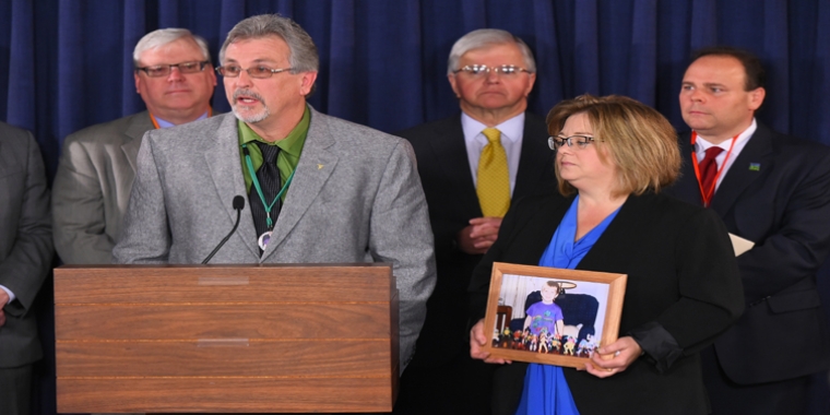 Dale and Dori Robie, holding a photo of their son Derrick, at this morning's news conference.